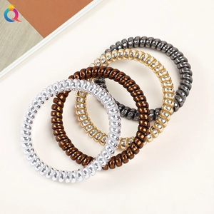 Macro shot of four metallic spiral hair ties in silver, brown, gold and grey shades