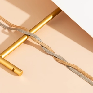 Detail of interlocking gold and silver flat snake bone chain necklaces with fine scales