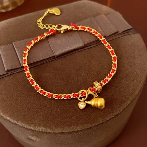Détail du bracelet en corde rouge plaqué or avec gourde mate et charms cœur zircon