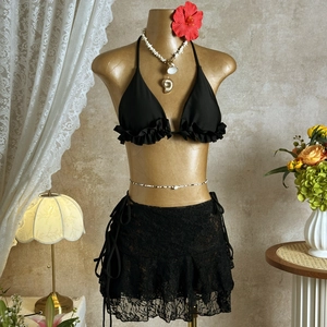 Detail of black halter ruffle bikini set with a lace drawstring beach cover-up skirt