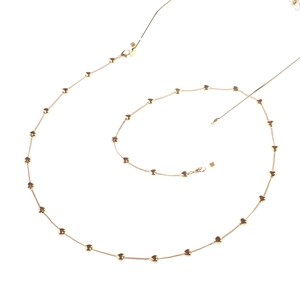 Detailed view of a gold heart-shaped eyewear chain with lobster clasp on a white background