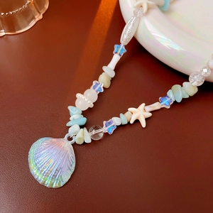 Macro shot of iridescent shell pendant with blue star beads and colorful stone beads