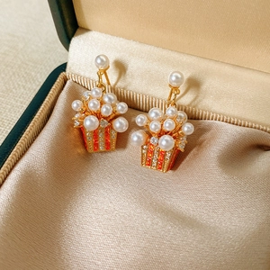 Detail of gold-plated popcorn earrings with pearls and orange zircon on satin