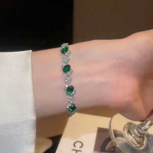 Detail of silver bracelet with oval green gemstones and diamonds worn on wrist