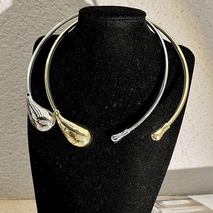 Detail of gold and silver teardrop choker necklaces on a black velvet mannequin display