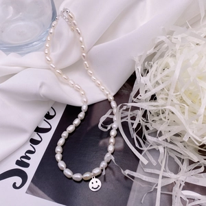 Macro shot of baroque pearl necklace with a silver smiling face metal pendant