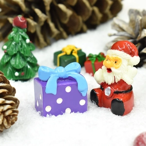Miniature Santa Claus figurine with purple polka dot gift box in a snowy scene