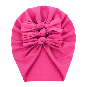 Detail of soft rose pink baby turban hat with triple-layered bow and knit texture