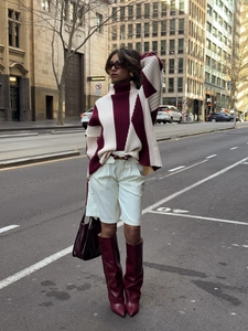 Street style view of a color-block turtleneck sweater paired with dark red leather boots