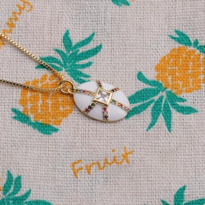 Détail du collier plaqué or avec zircons multicolores sur un pendentif ovale blanc