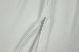 Detailed close-up of white fabric texture showing precision stitching and side slit detail