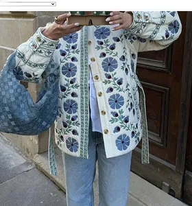 Détail de la broderie florale sur veste matelassée avec boutons en bois et ceinture