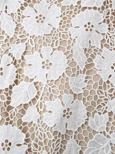 Gros plan détaillé de la dentelle florale blanche avec doublure beige sur robe élégante