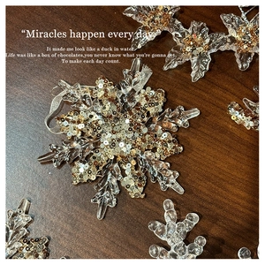 Close-up of clear acrylic snowflake ornament with sparkling gold sequins and silver string