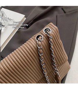 Close-up of silver grommets and leather-woven chain strap on brown quilted shoulder bag