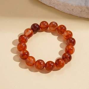 Detailed view of red agate beaded bracelet with natural textures on warm beige background