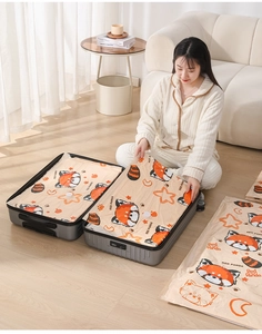 Woman packing cute red panda printed vacuum storage bags into a suitcase in a room