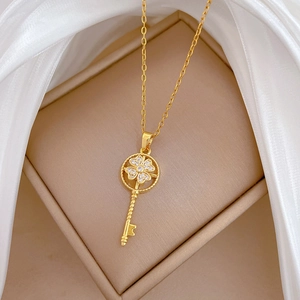 Macro view of gold clover key necklace with sparkling zircons on champagne satin