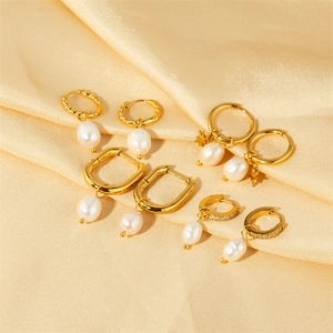 Detailed macro view of various gold U-shaped hoop earrings with white pearls on silk