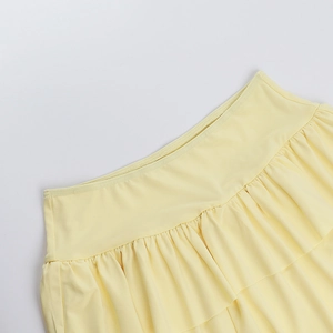 Detailed close-up showing the waistline craft and layered pleated texture of the yellow skirt