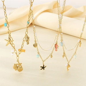 Layered gold necklaces with starfish, seahorse and pearls on beige silk fabric