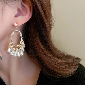 Gros plan de boucles d'oreilles vintage dorées avec cristaux brillants et pompons de perles