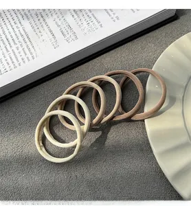 Close-up of five elastic hair ties in earth tones on a minimalist textured surface