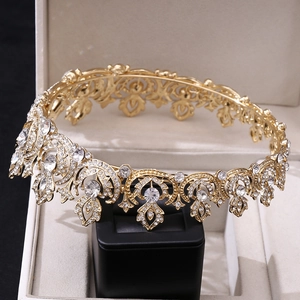 Close-up of golden hollow metal crown with clear rhinestones on a black display stand