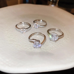 Detailed view of four silver adjustable zircon rings on a white ceramic display tray