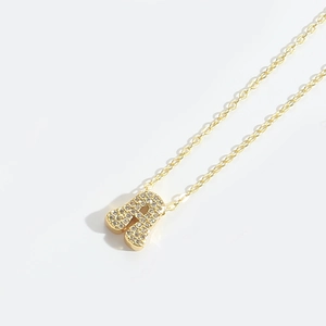 Detailed close-up of golden letter A pendant with clear zircons on a delicate chain