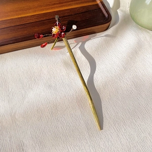 Detailed macro shot of vintage bronze hair pin with red resin flower and white pearls