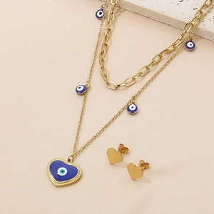 Detail of gold layered necklace and heart earrings set with blue evil eye motifs