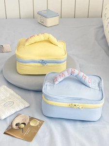Detail of color-block travel toiletry bags with embroidered handles and metal zippers