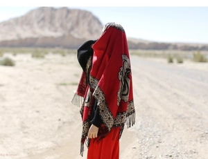 Close-up of red cashmere shawl with black paisley patterns and fringe in desert