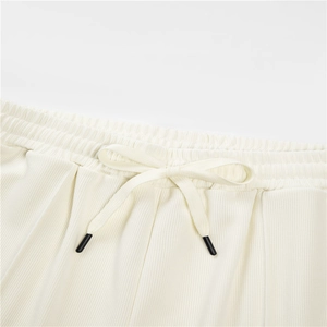 Detail of high-waist drawstring waistband and ribbed fabric texture on white joggers