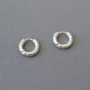 Macro detail of silver hammered texture on circular hoop earrings with a metallic finish