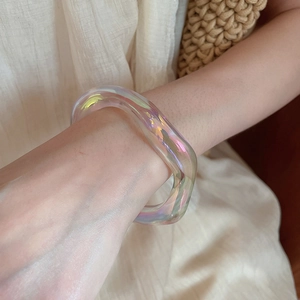 Close-up of irregular iridescent acrylic bracelet worn on wrist with minimalist design