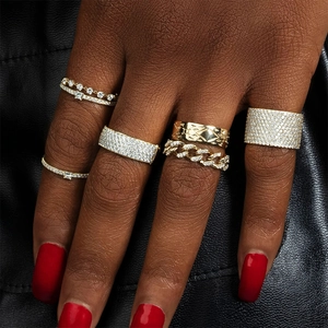 Close-up of stacked 18K gold plated rings with cubic zirconia on hand with red nails