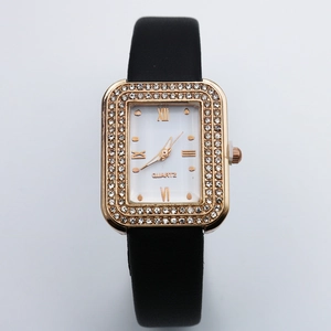 Close-up of rectangular gold watch case with crystal diamond bezel and black leather strap