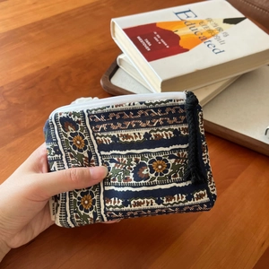 Detail of bohemian mini coin purse with floral pattern and black tassel zipper pull