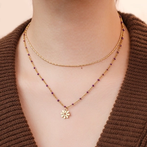 Close-up of double-layer bohemian gold necklace with purple beads and daisy petal pendant