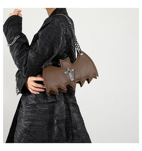 Detail of brown leather bat-shaped bag with silver cross buckle and metal chain strap