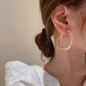 Minimalist double hoop earrings in gold metal finish worn by model for elegant style