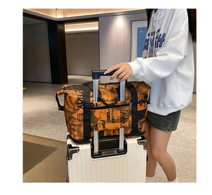 Detail of the orange graffiti travel bag with a trolley sleeve for easy luggage attachment