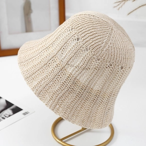 Minimalist beige hollow knit bucket hat with bow detail on a stylish display stand