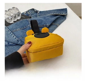 Detalle del mini bolso amarillo de tela oxford con orejas decorativas y asa superior