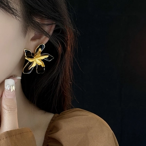 Close-up of vintage-style double layered gold and black enamel flower earrings on a model