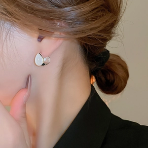 Close-up of minimalist silver hoop earrings with white cat eye stone worn by a model