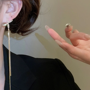 Gros plan sur des boucles d'oreilles dorées à pampilles avec motif X en cristal
