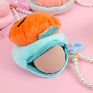 Macro shot of plush carrot coin purse featuring a pearl chain and blue hook detail